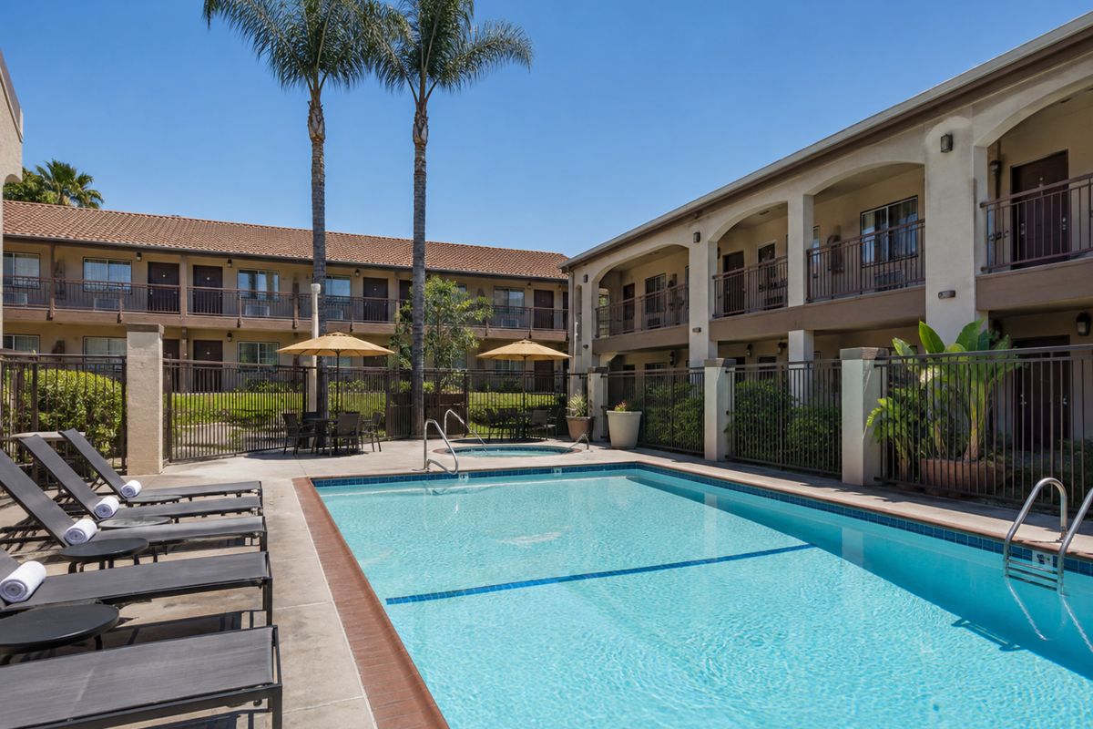 Community pool with lounge chairs beside a clubhouse