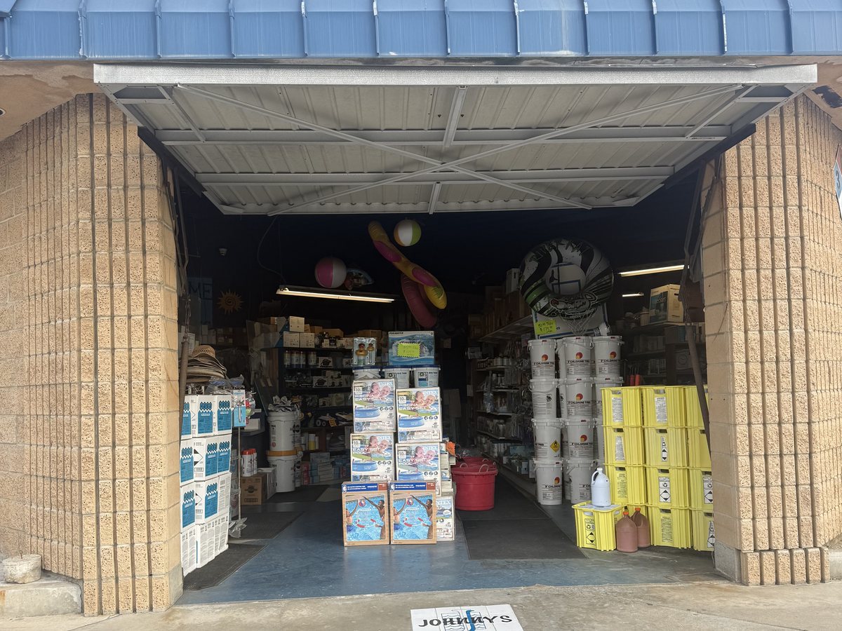 Buckets of chlorine tabs and pool supplies stacked inside Johnny's